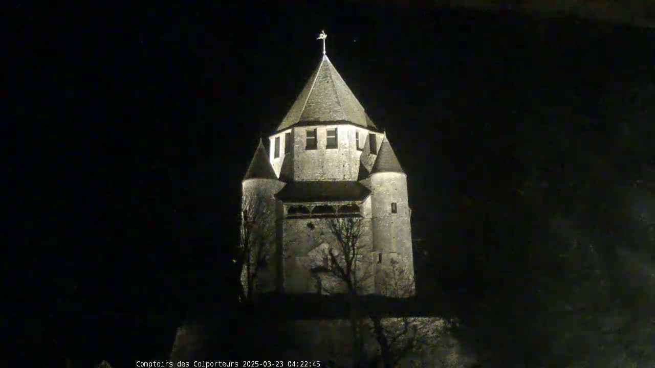 A stone tower, illuminated at night, stands against a dark sky.