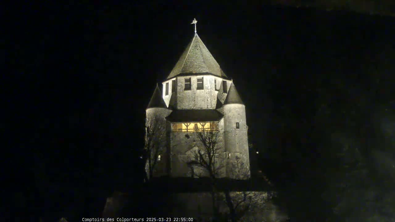 A stone tower, illuminated at night, stands against a dark sky.