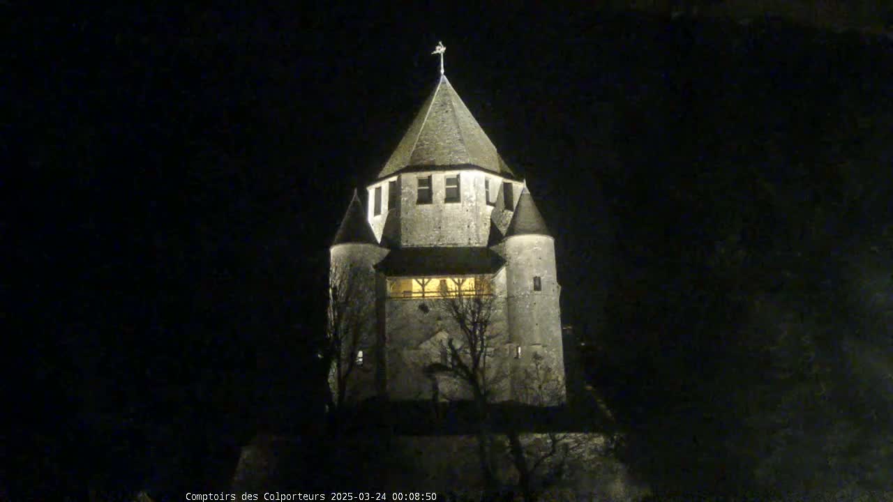 A stone tower, illuminated at night, stands against a dark sky.
