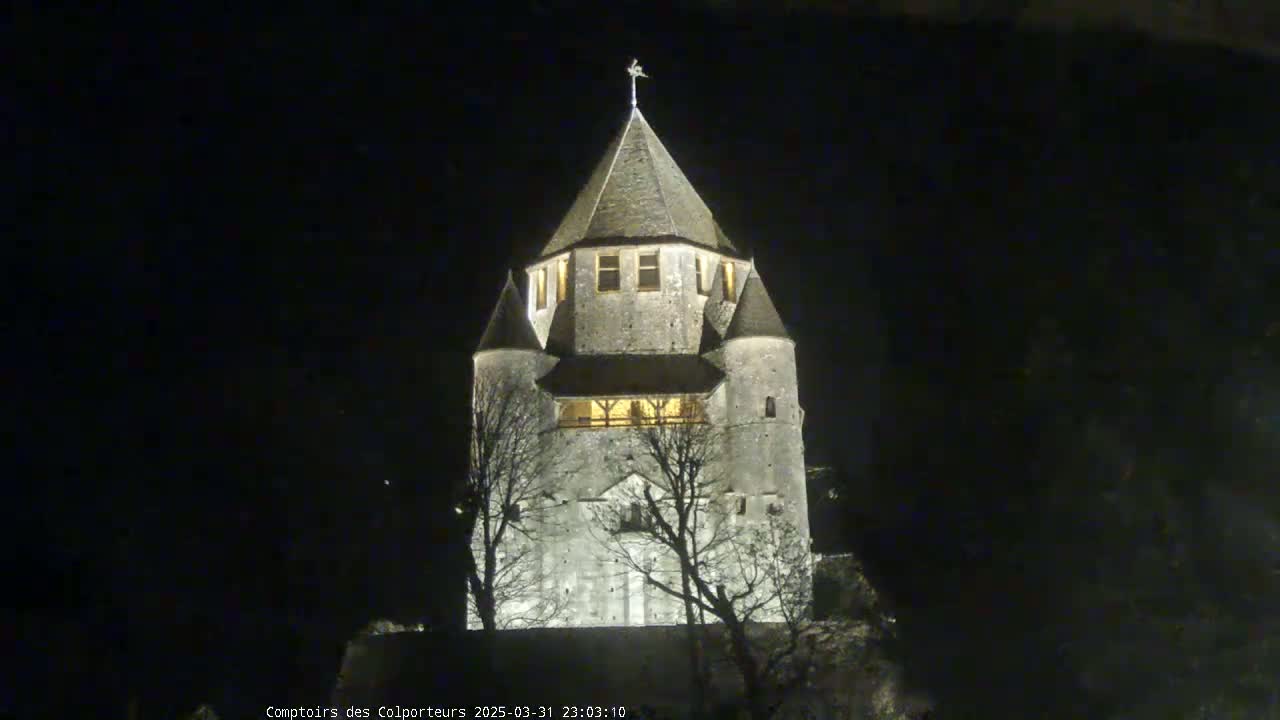 A stone tower, illuminated at night, stands against a dark sky.