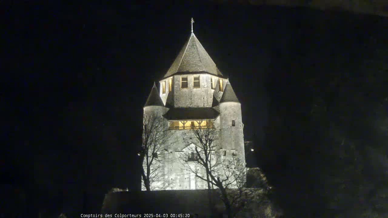 A stone tower, illuminated at night, stands silhouetted against a dark sky.