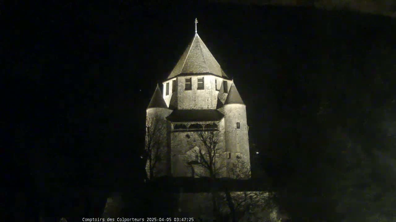 A tall, stone tower, illuminated at night, stands against a dark sky.