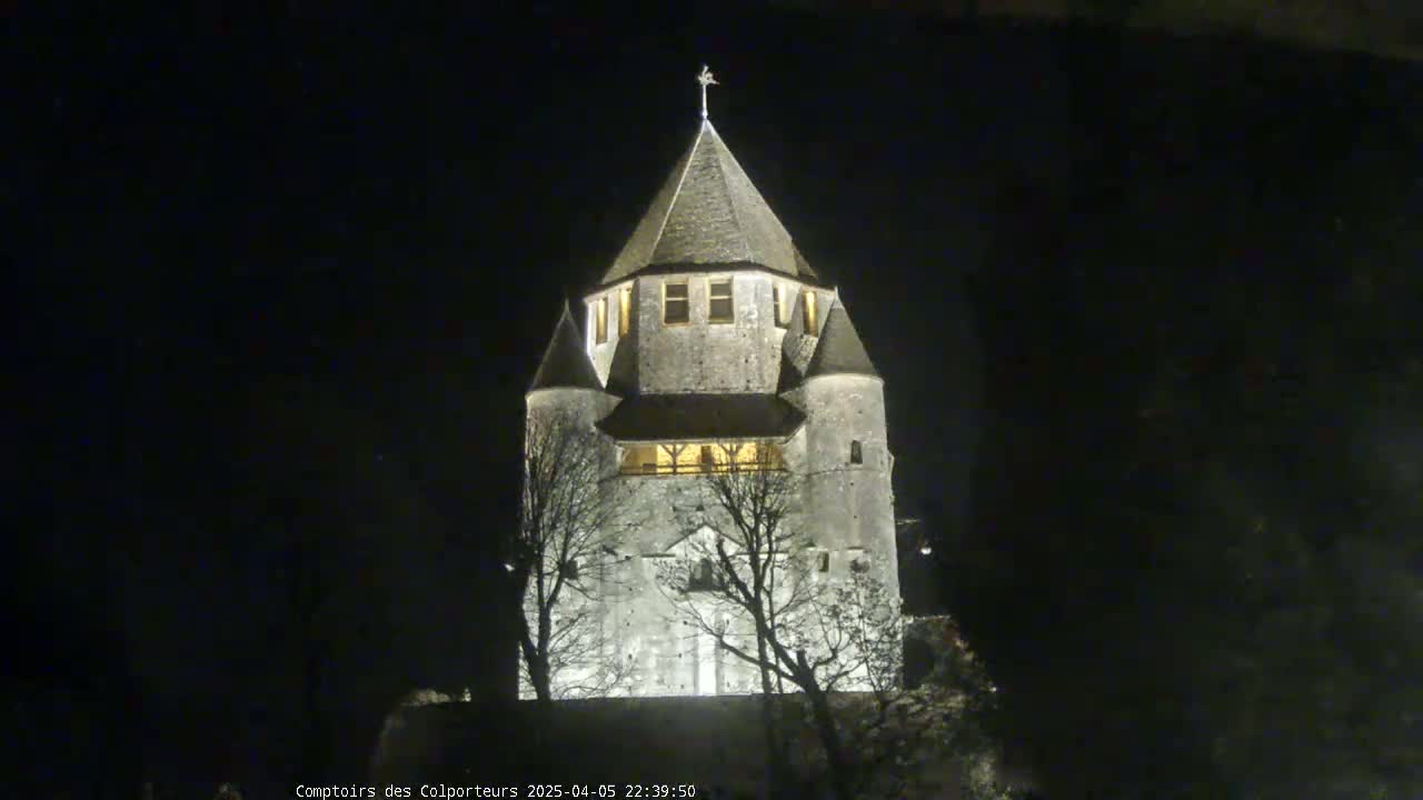 A stone tower, illuminated at night, stands silhouetted against a dark sky.