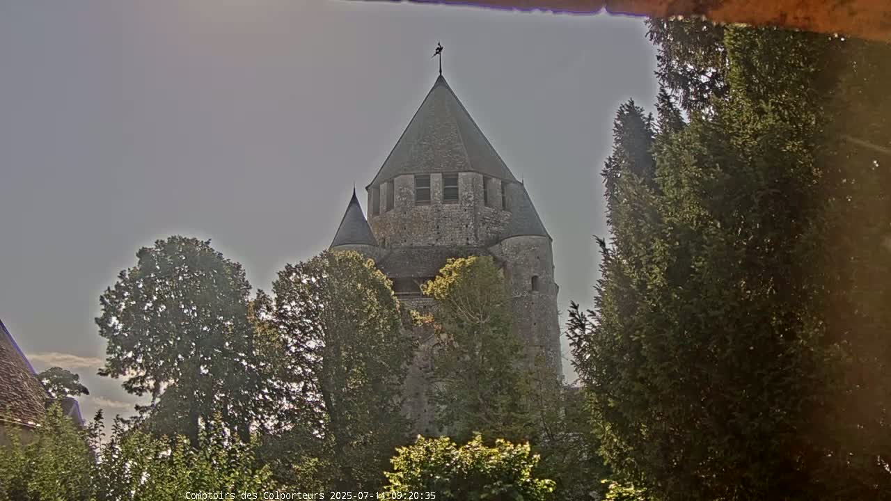 A stone tower, partially obscured by trees, is visible under a bright, overcast sky.
