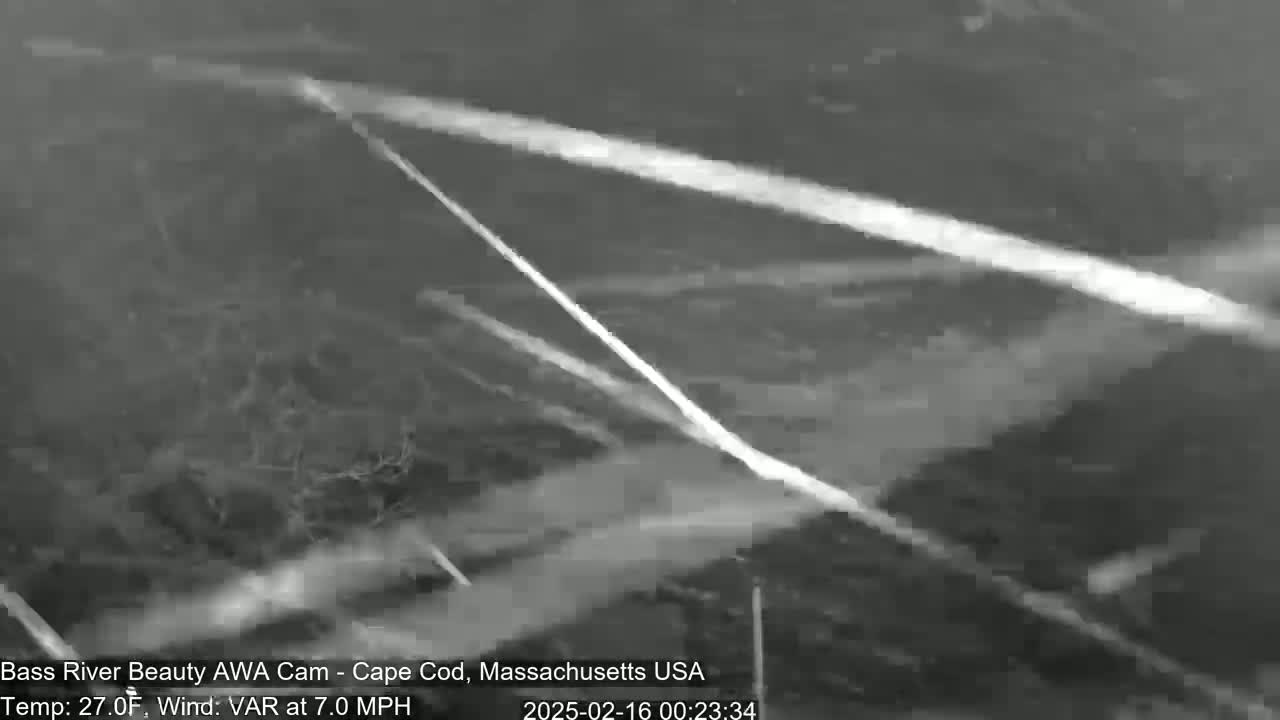 A nighttime, grayscale outdoor scene shows bright streaks across a dark, possibly snowy or overcast sky, with a 7.0 mph wind and 27°F temperature.