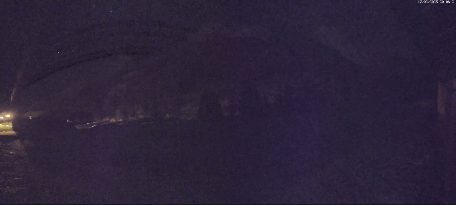 A dark, nighttime scene shows a shadowy, indistinct structure under a mostly clear sky.