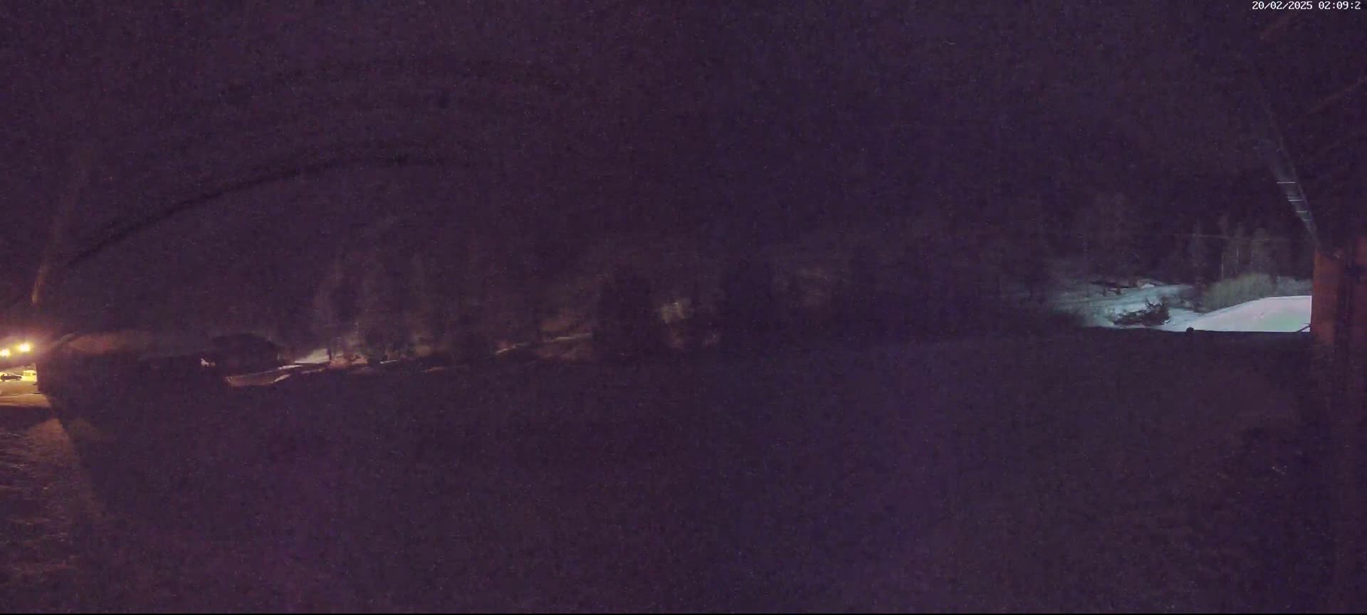 A nighttime, snow-covered landscape is visible, with dark trees and dimly lit areas in the background.