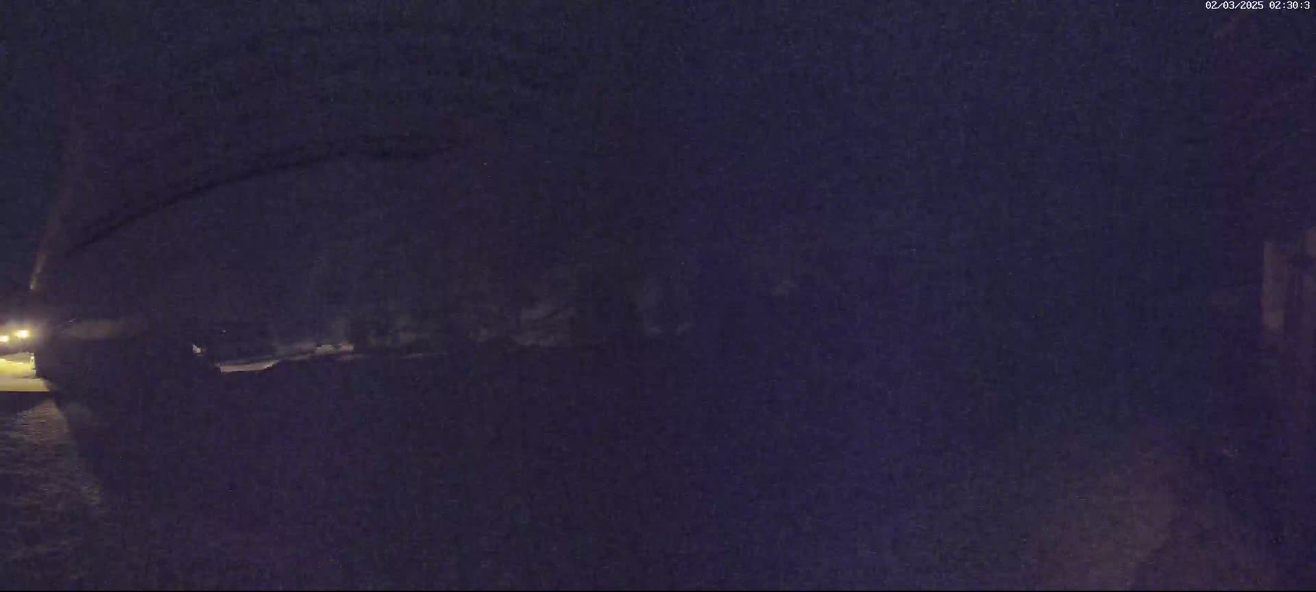 A dark, nighttime scene shows a vehicle partially obscured by shadows and low-light conditions.