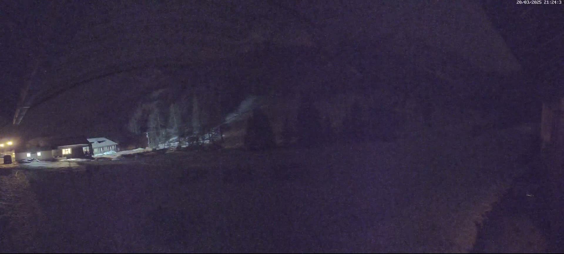 A dimly lit house is visible at night under a snowy, dark sky.