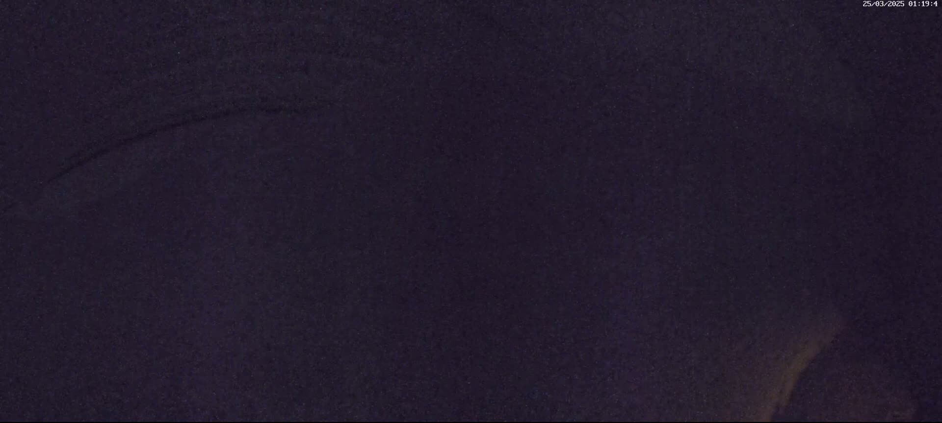 A dark, possibly nighttime image shows a textured, dark purple surface with a faint, lighter streak across it.