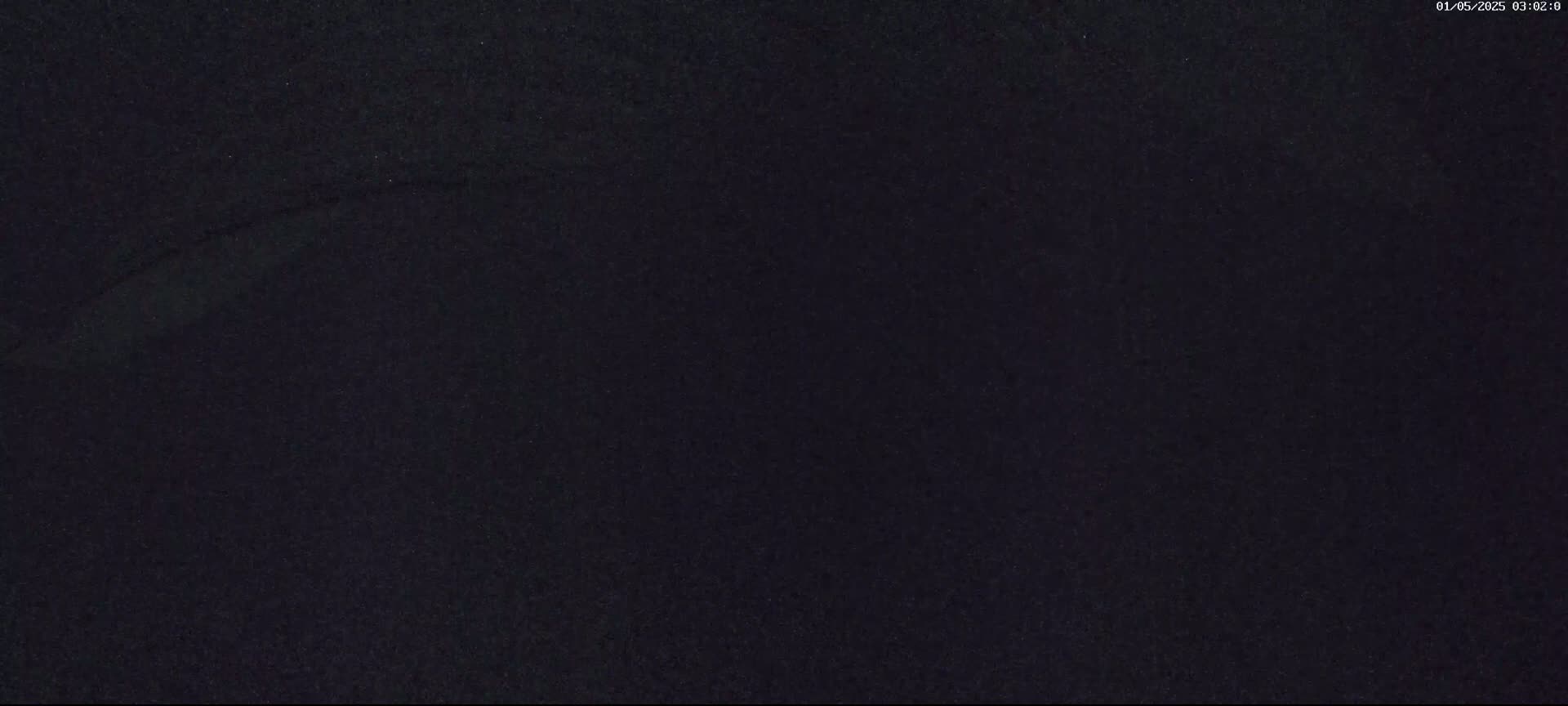 A dark, grainy image shows a mostly featureless black surface with a faint, curved line visible.