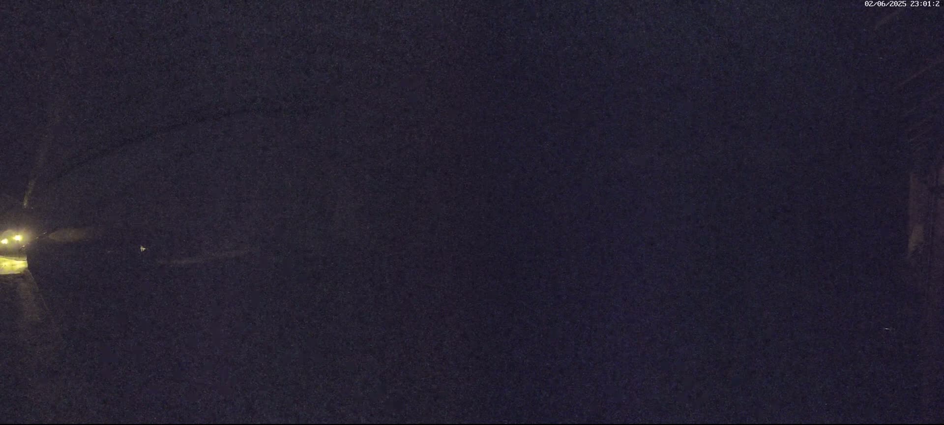 A nighttime view shows a dark, possibly wooded area with faint lights visible in the lower left corner.