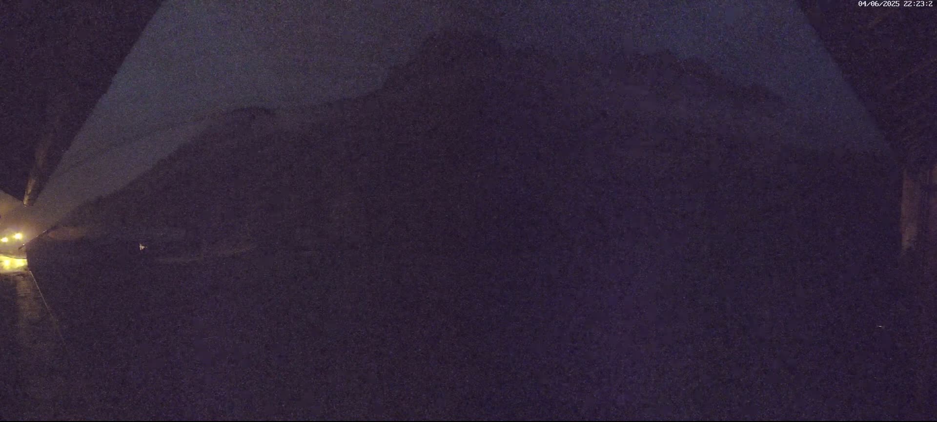 A dark, nighttime view shows a blurry, shadowy landscape with faint, distant lights.