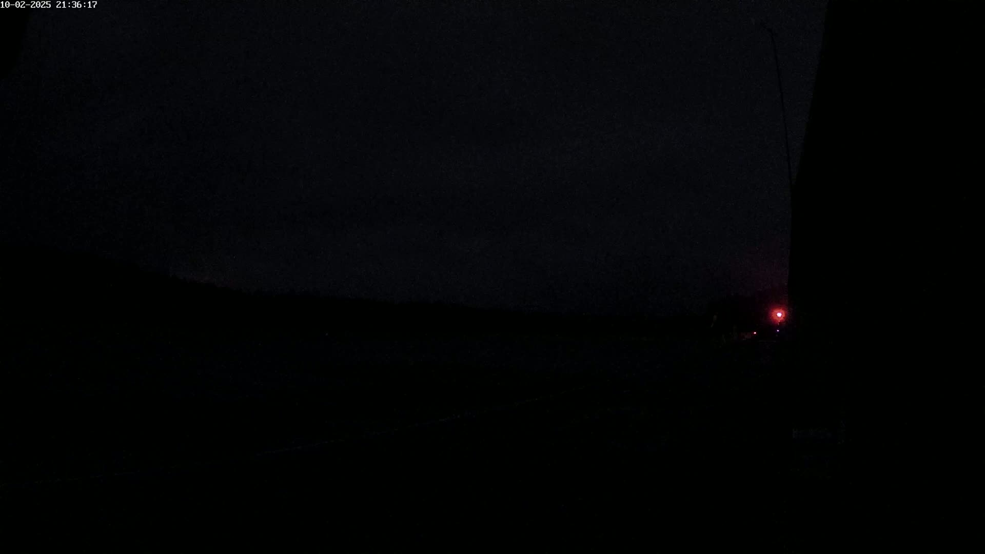 A dark, nighttime scene shows a faint red light in the distance.