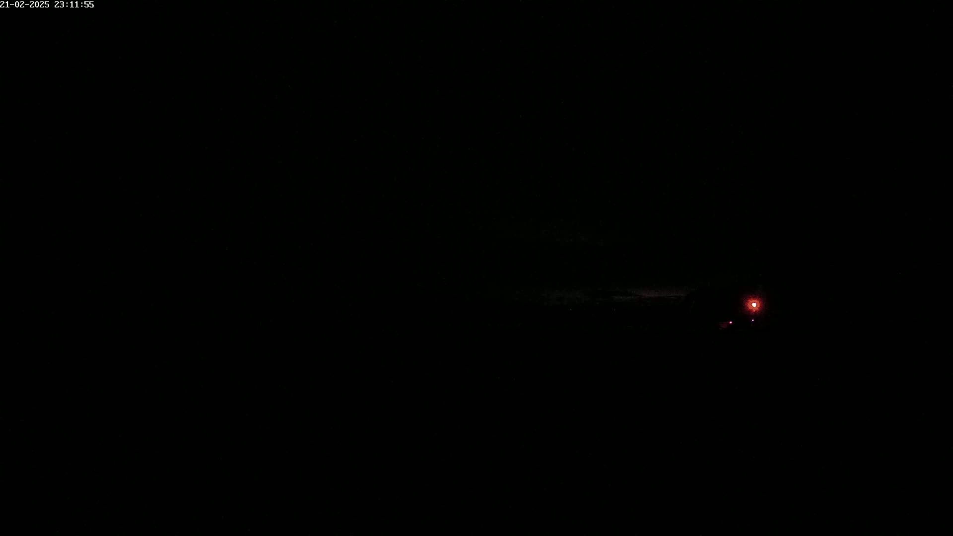 A faint red light is visible in the distance at night.