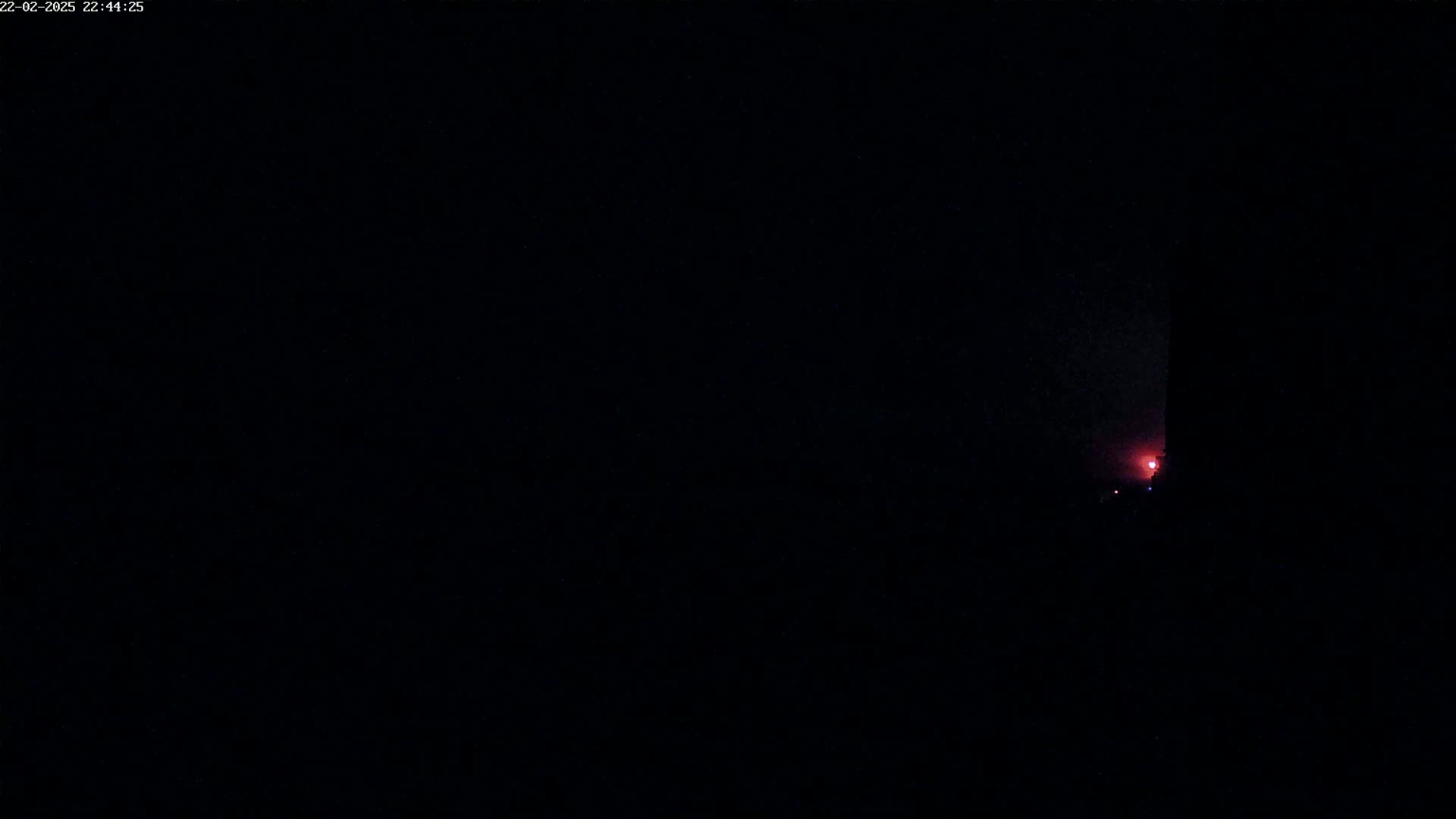 A faint reddish glow is visible in the distance against a very dark, nighttime sky.