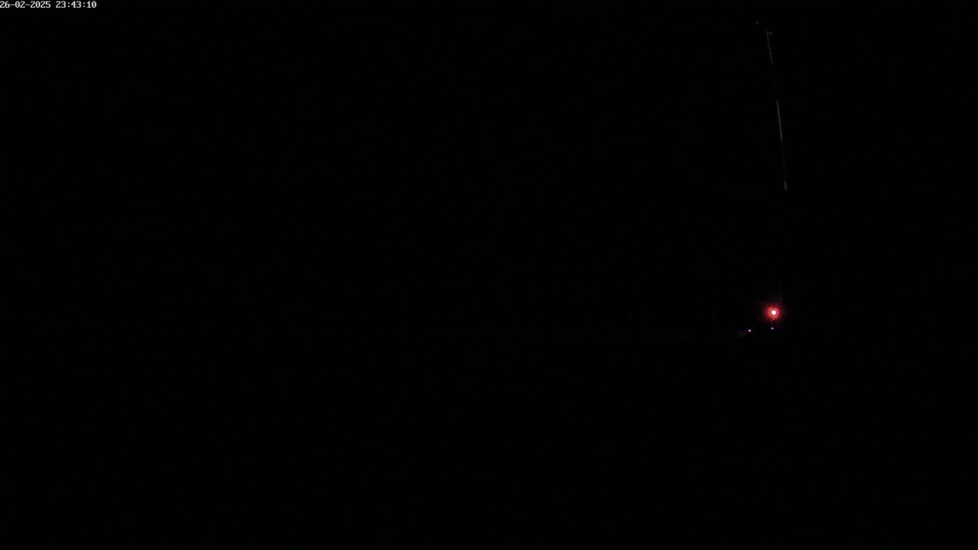 A small, faint red light is visible in the distance on a very dark, nighttime scene.