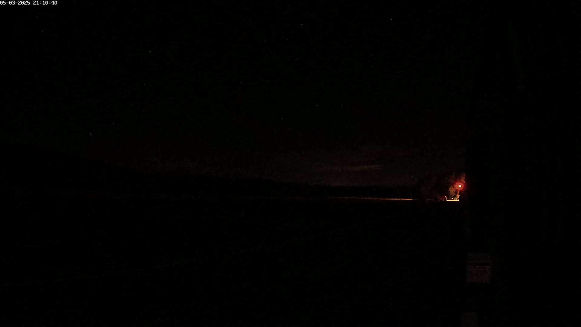 A dark, nighttime scene shows a dimly lit horizon under a starry sky.