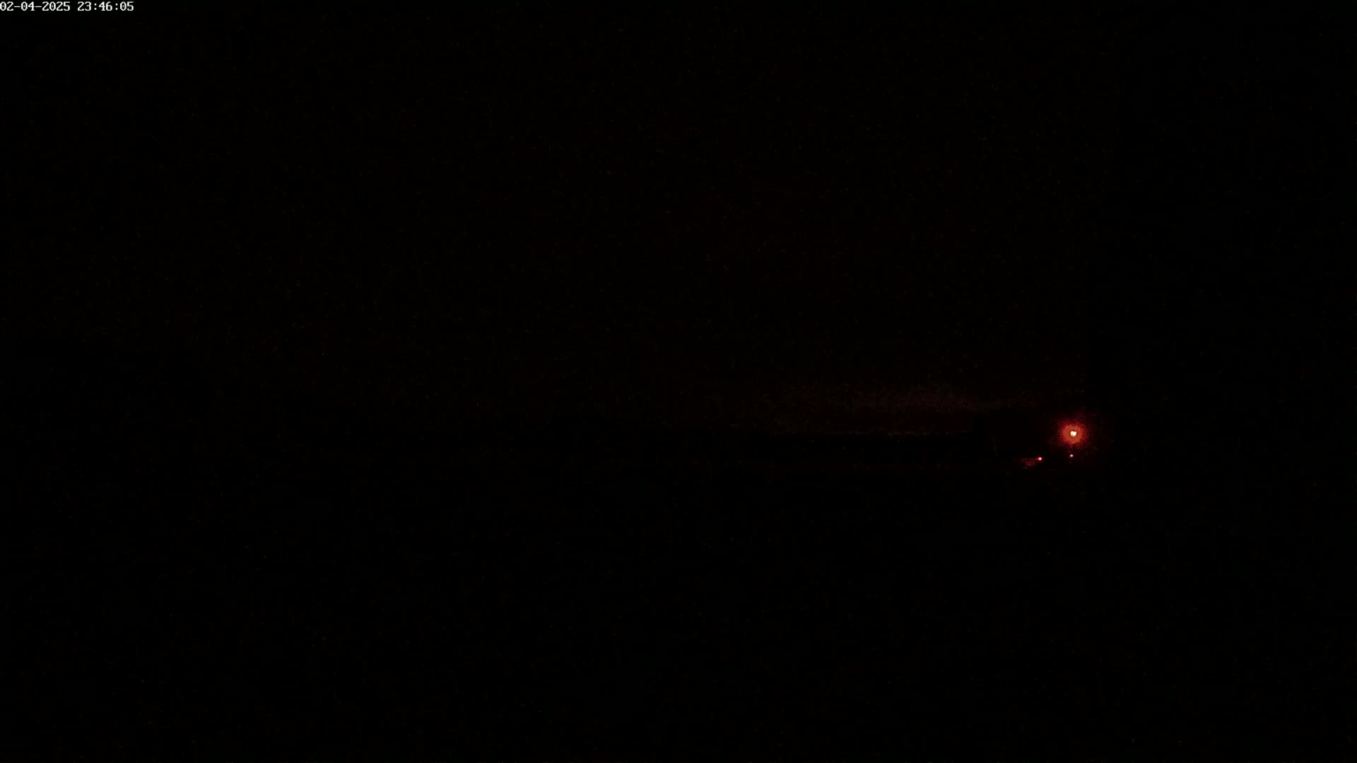 A dark, nighttime scene shows a faint reddish glow on the horizon.