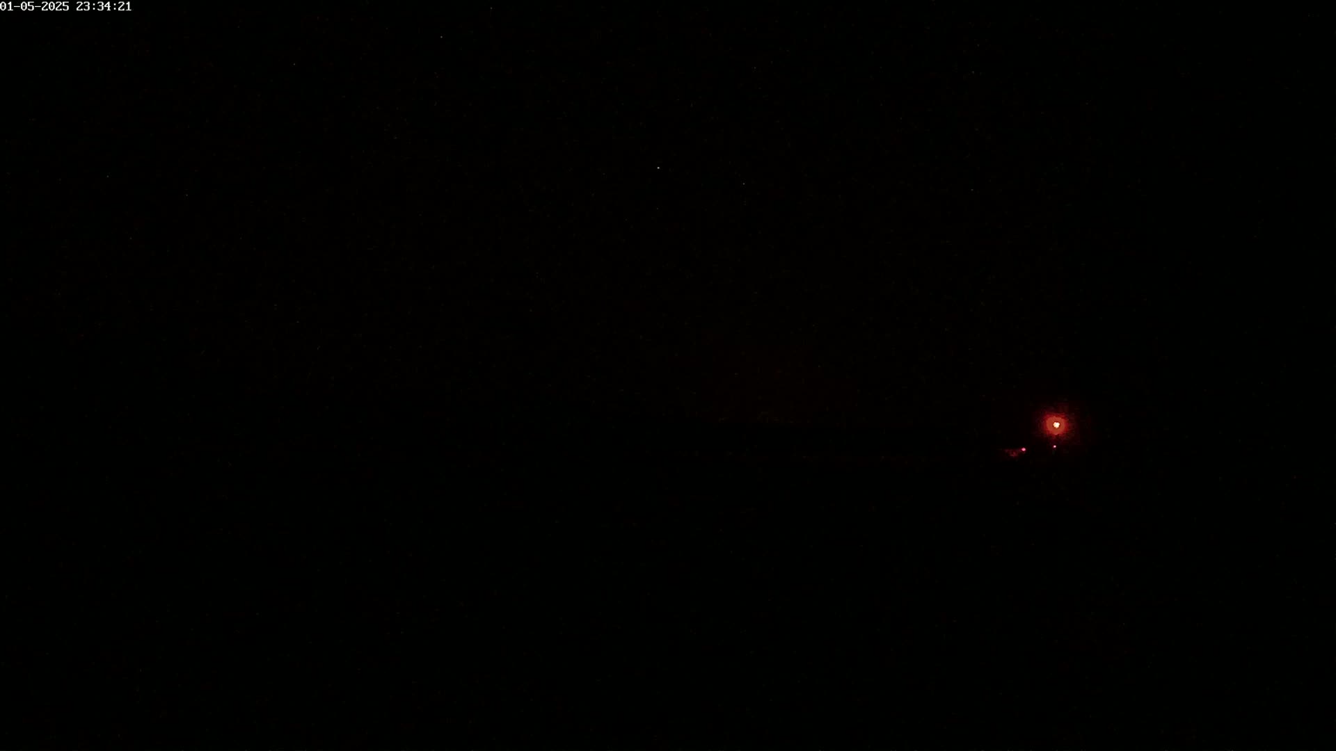A dark night scene shows a faint red light in the distance.