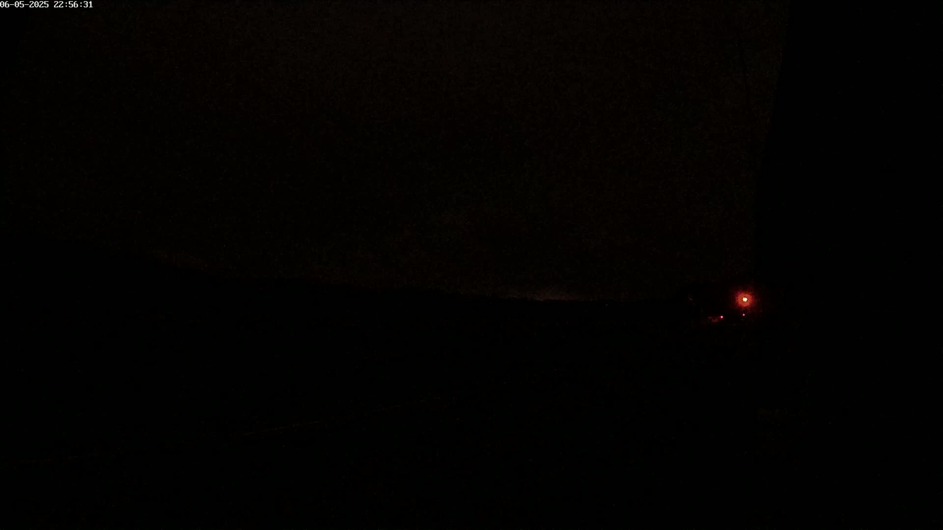 A dark, nighttime scene shows a faint, distant red light.