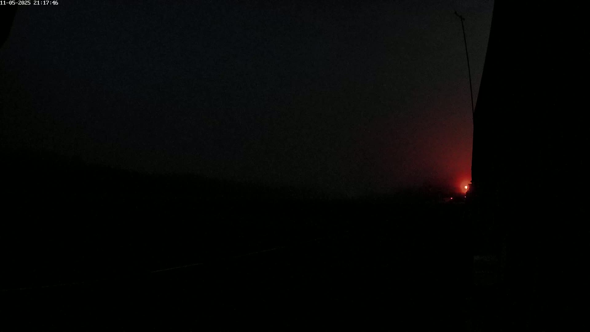 A low-light, hazy sunset is visible on the horizon, partially obscured by a dark, silhouetted structure.