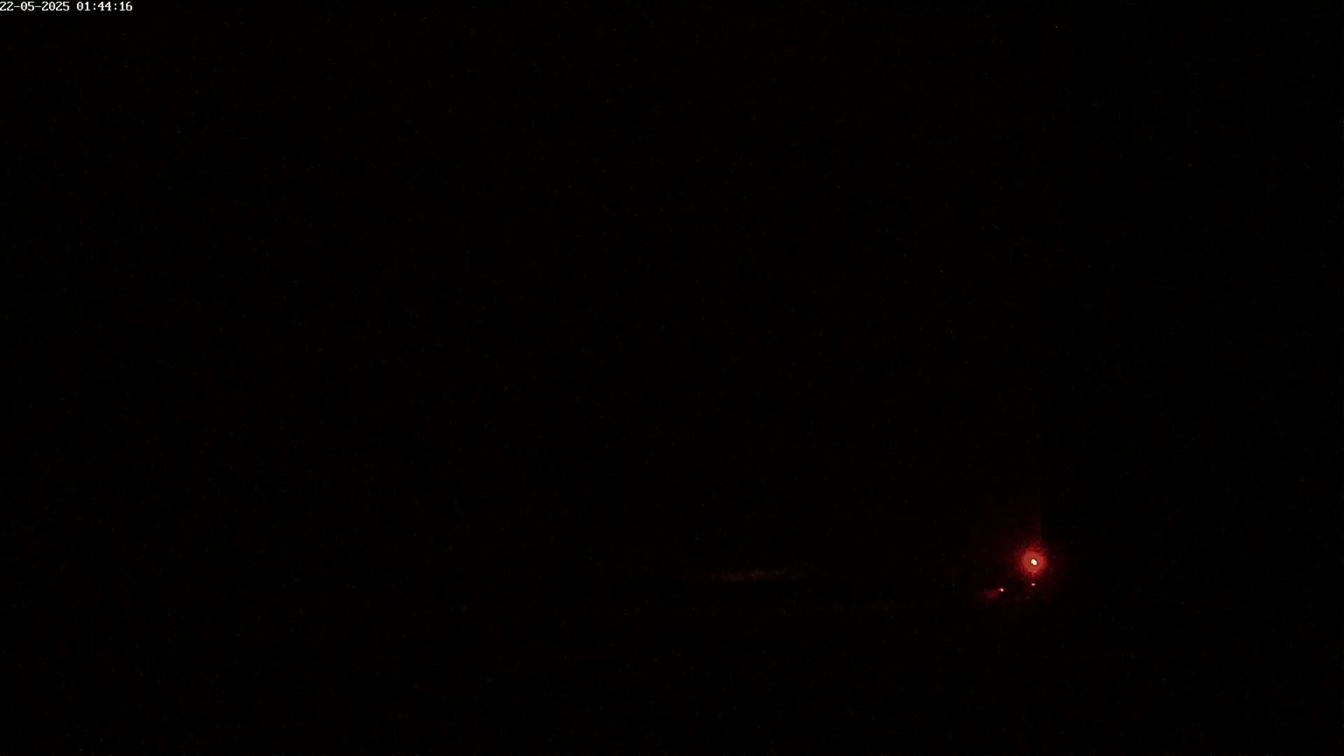 A faint red light is visible in the lower right corner of a completely dark nighttime scene.