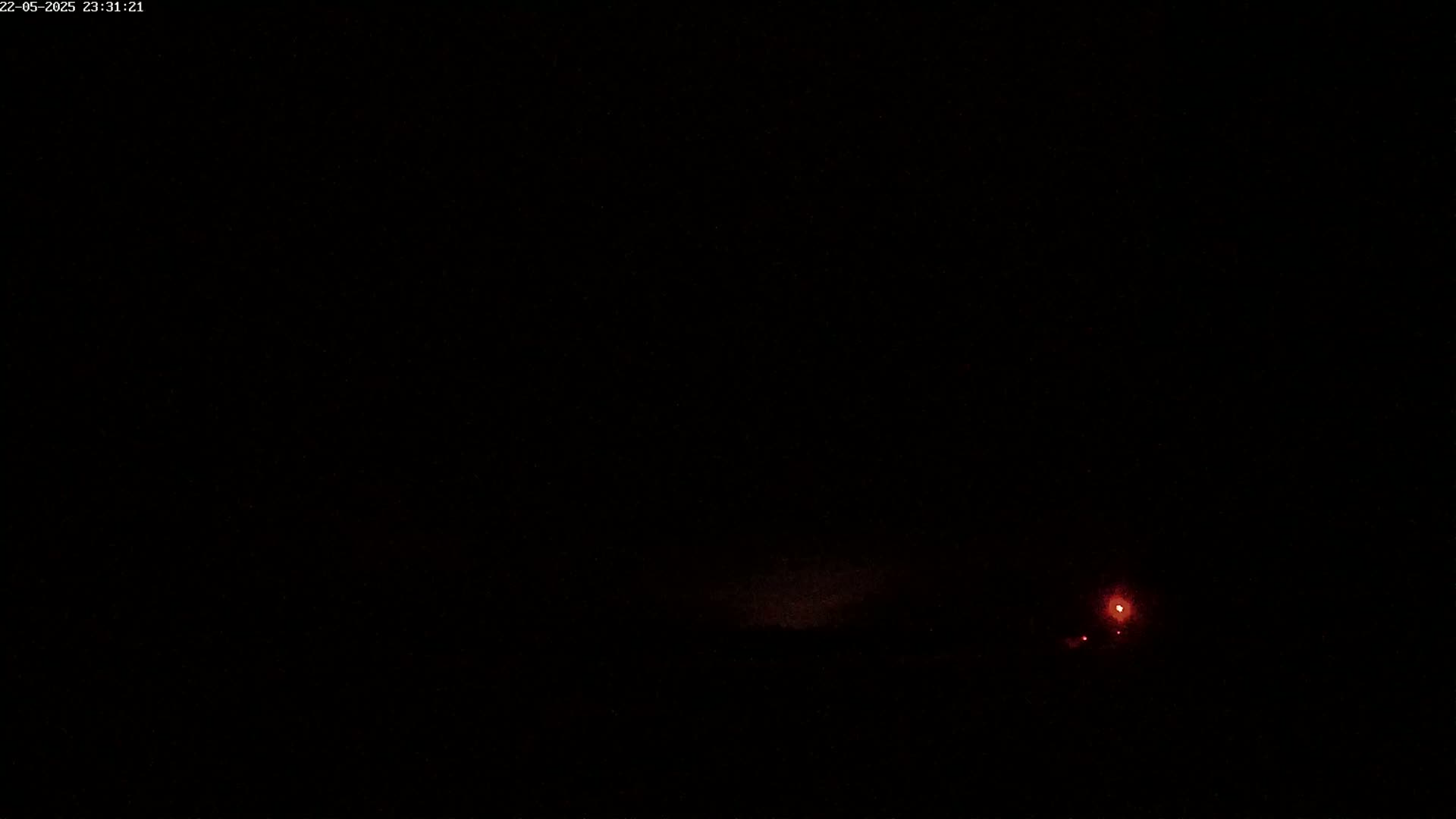 A dark, nighttime scene shows a faint reddish glow on the horizon.