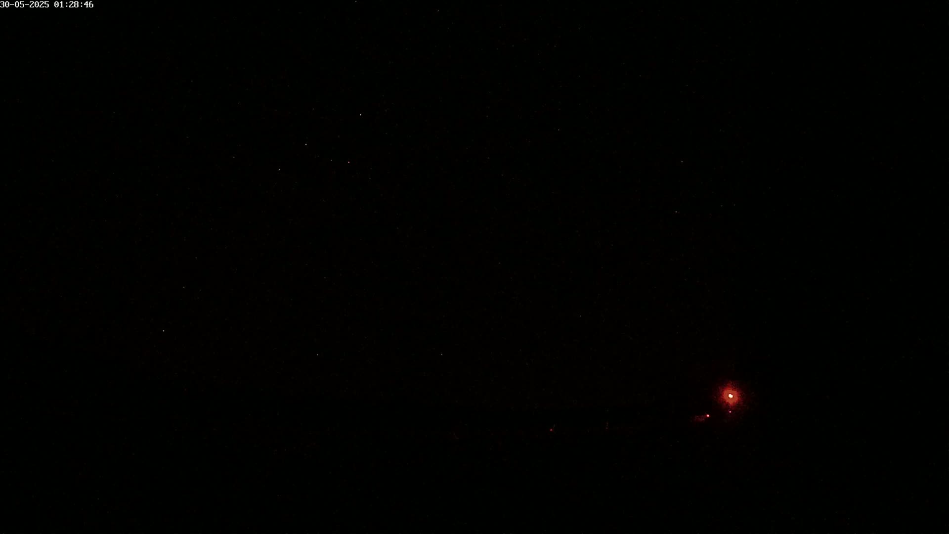 A dark night sky shows a few stars and a distant, faint red light.