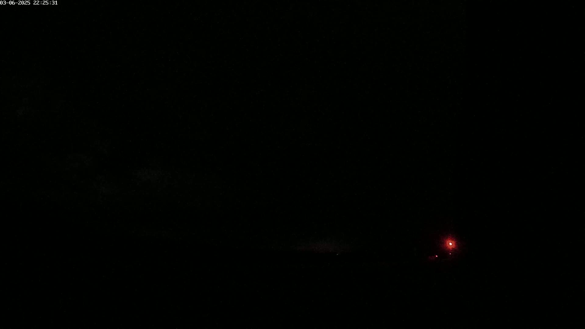 A nighttime outdoor scene shows a faint reddish glow on the horizon.
