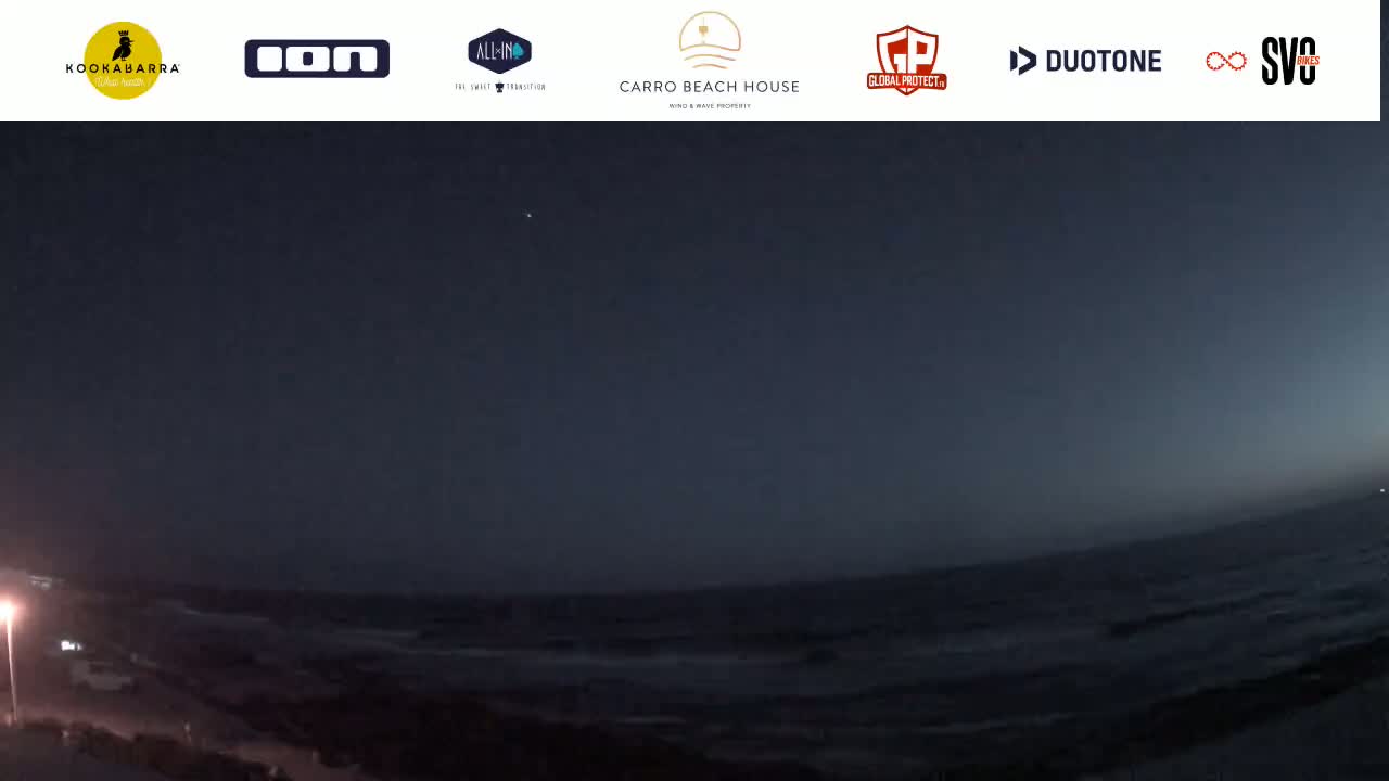 A nighttime, wide shot shows a dark ocean with small waves under a mostly clear, dark sky.