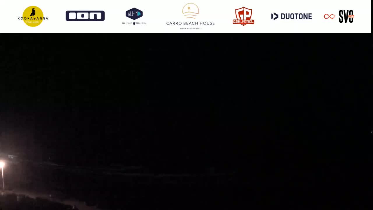 A nighttime, dark scene of an ocean shore is visible, illuminated only by a single light source on the left.