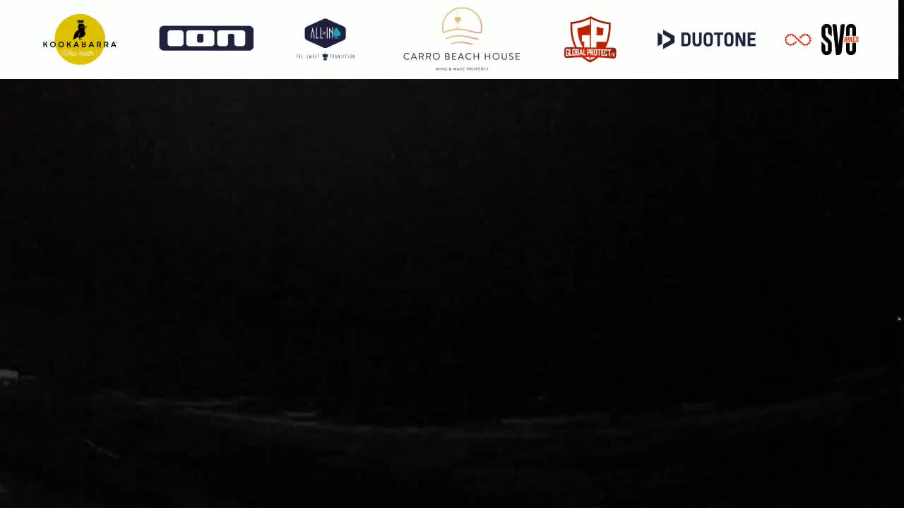 A dark, nighttime scene shows a mostly black landscape with a faint suggestion of a wavy shoreline.