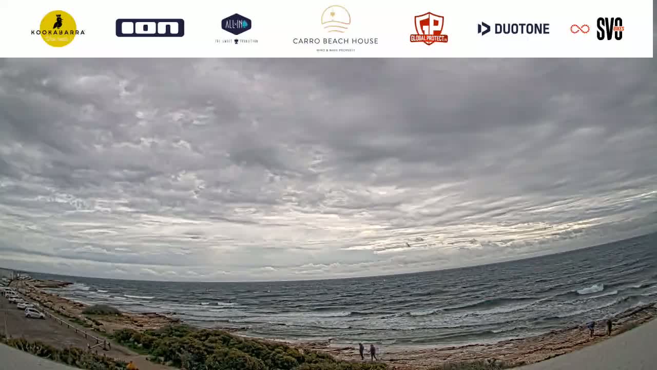 A wide shot of a rocky shoreline with a somewhat choppy ocean under a mostly cloudy sky.