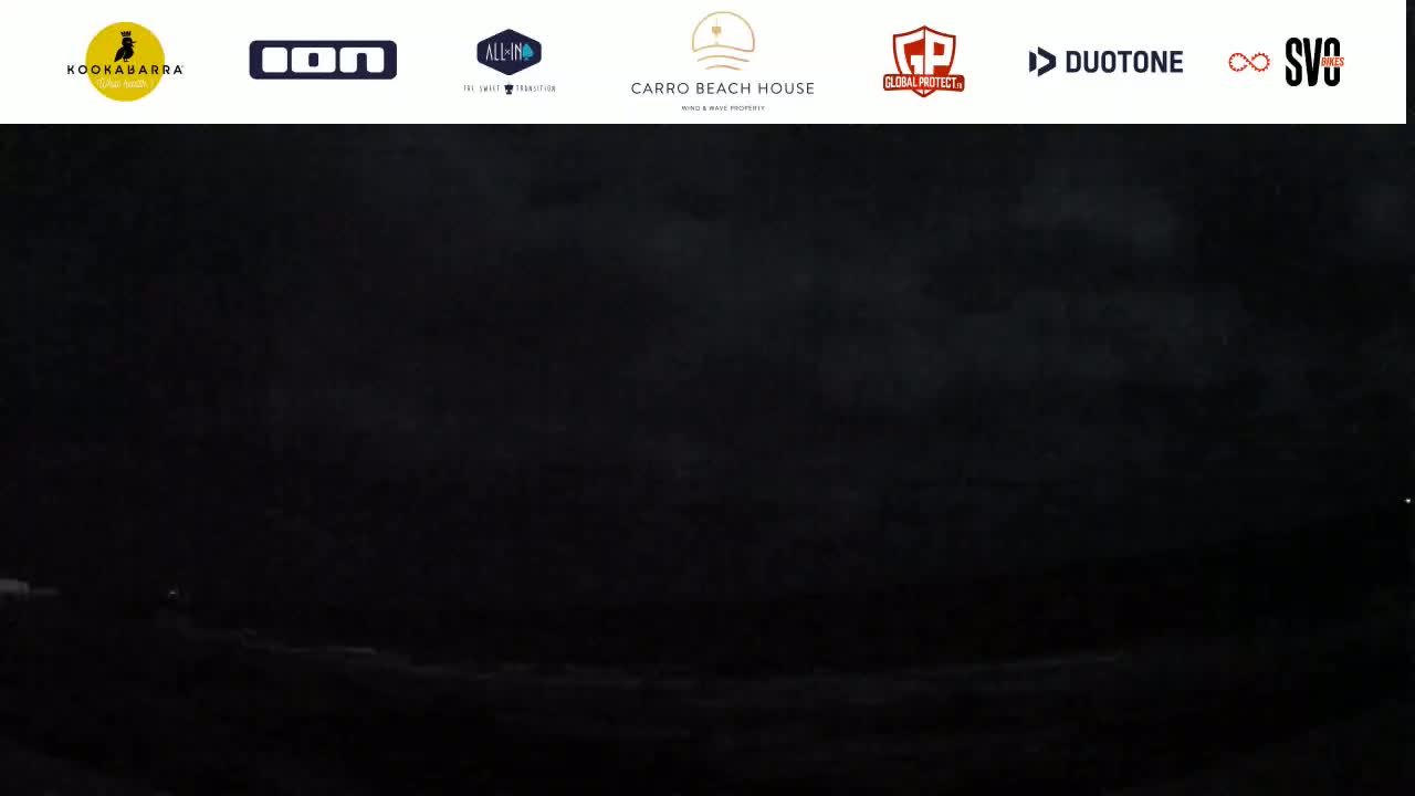 A dark, nighttime scene shows a mostly obscured body of water under a cloudy sky.