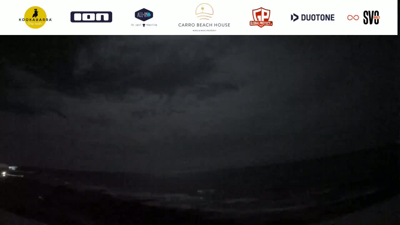 A dark, nighttime coastal scene shows an overcast sky and a barely visible body of water.
