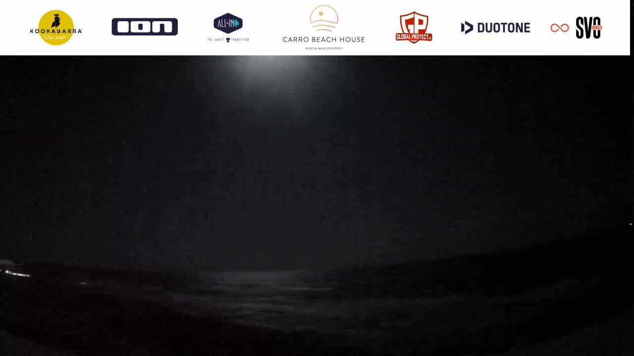 A dark, nighttime scene shows a body of water under a hazy, brightly lit sky.