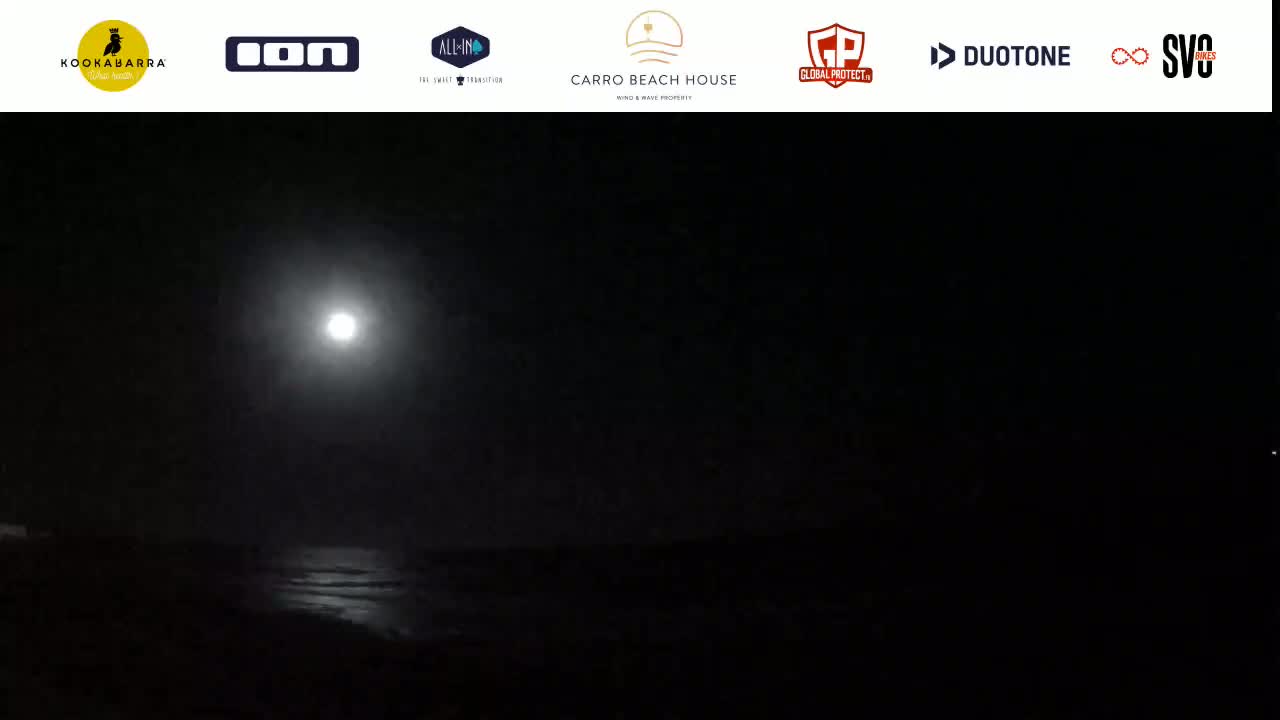 A bright moon illuminates a dark, seemingly calm body of water at night.