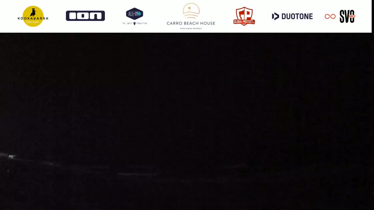 A dark, nighttime scene shows a faint, indistinct shoreline with minimal light visible.
