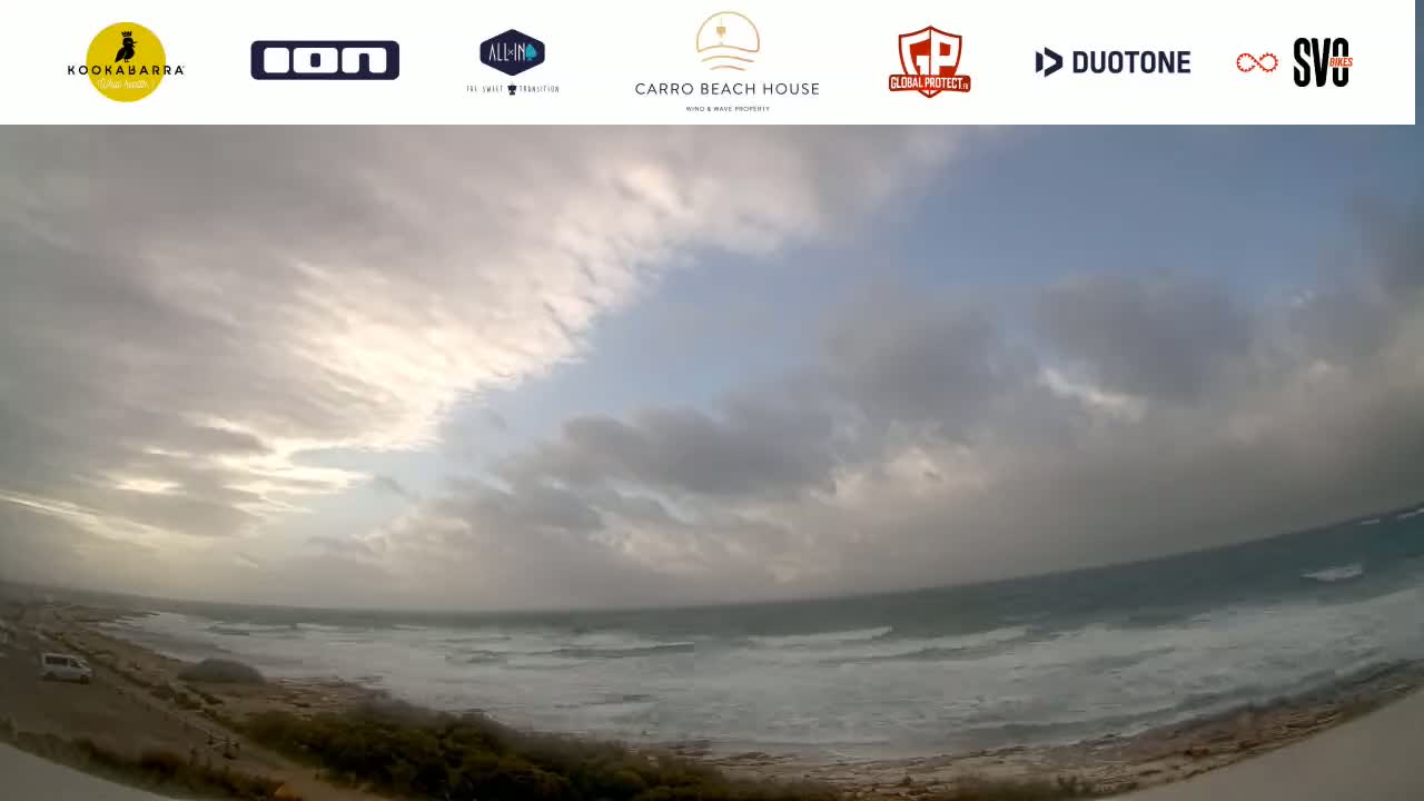 A wide shot shows a cloudy, somewhat overcast sky over a rocky coast with a choppy ocean.