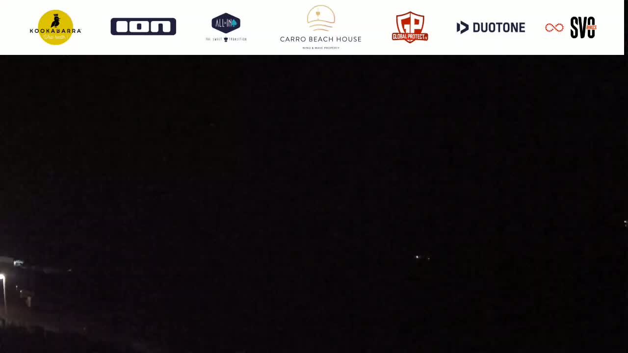 A dark, nighttime scene shows a few faint lights in the distance.