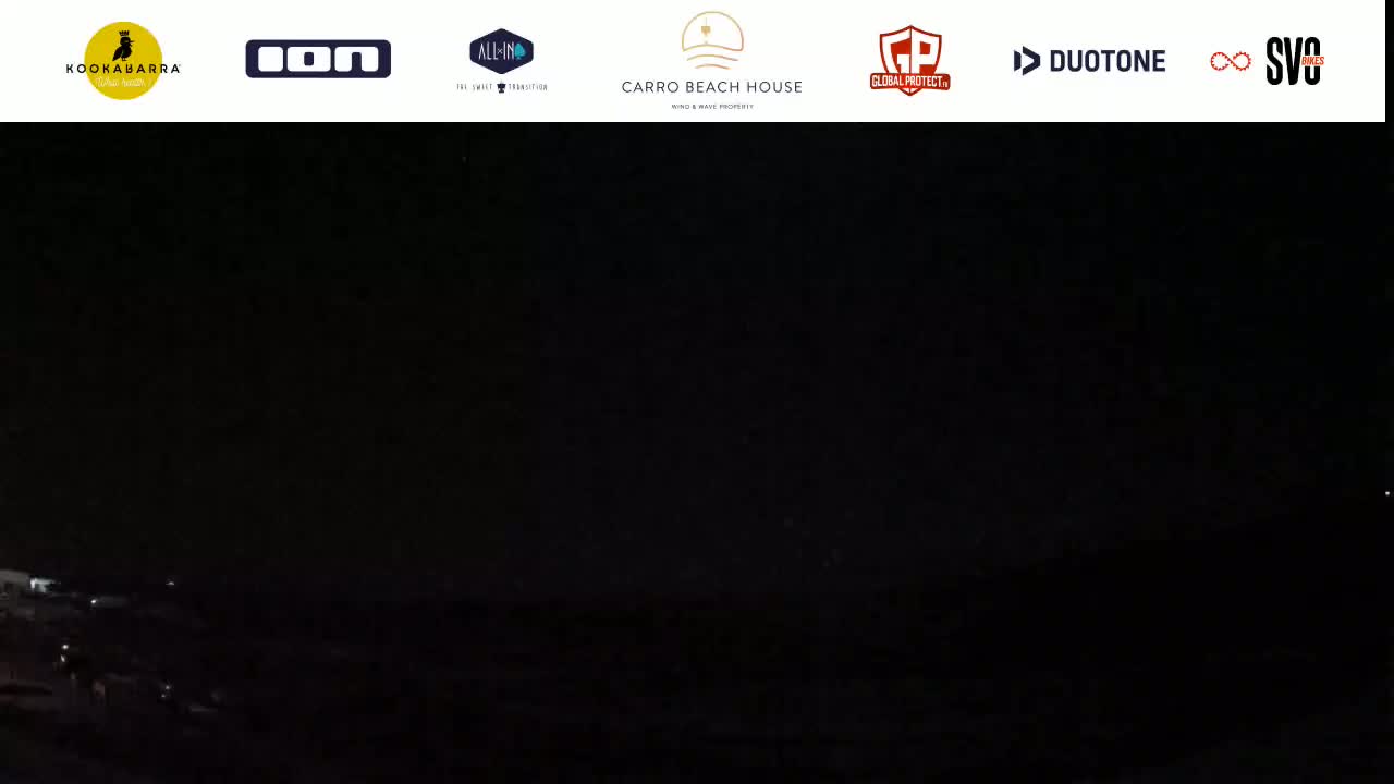 A dark nighttime scene shows a dark body of water and land under a mostly clear, black sky.
