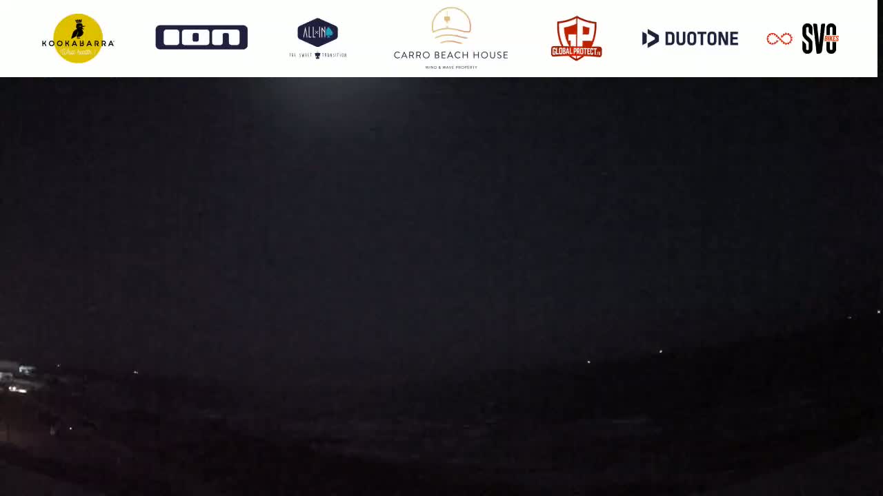 A nighttime, dark, and overcast view of a landscape with a few distant lights visible.