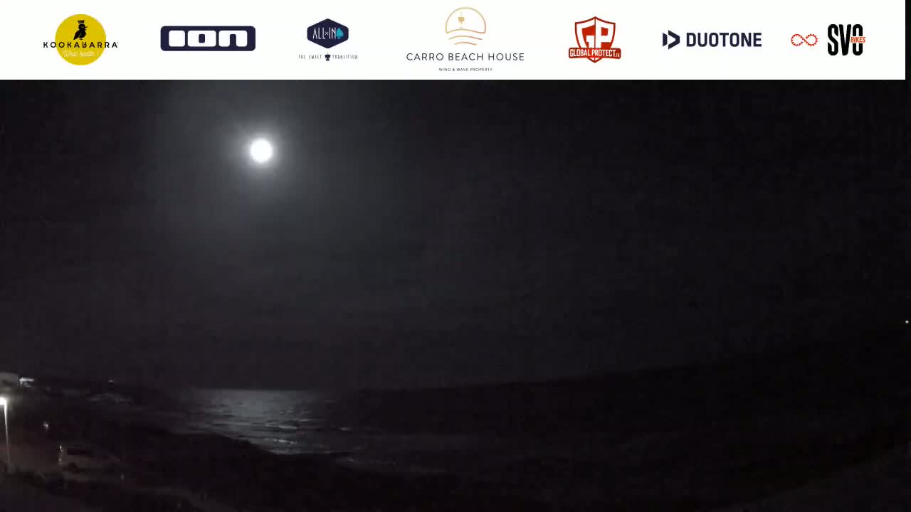 A bright moon illuminates a dark, nighttime ocean scene.