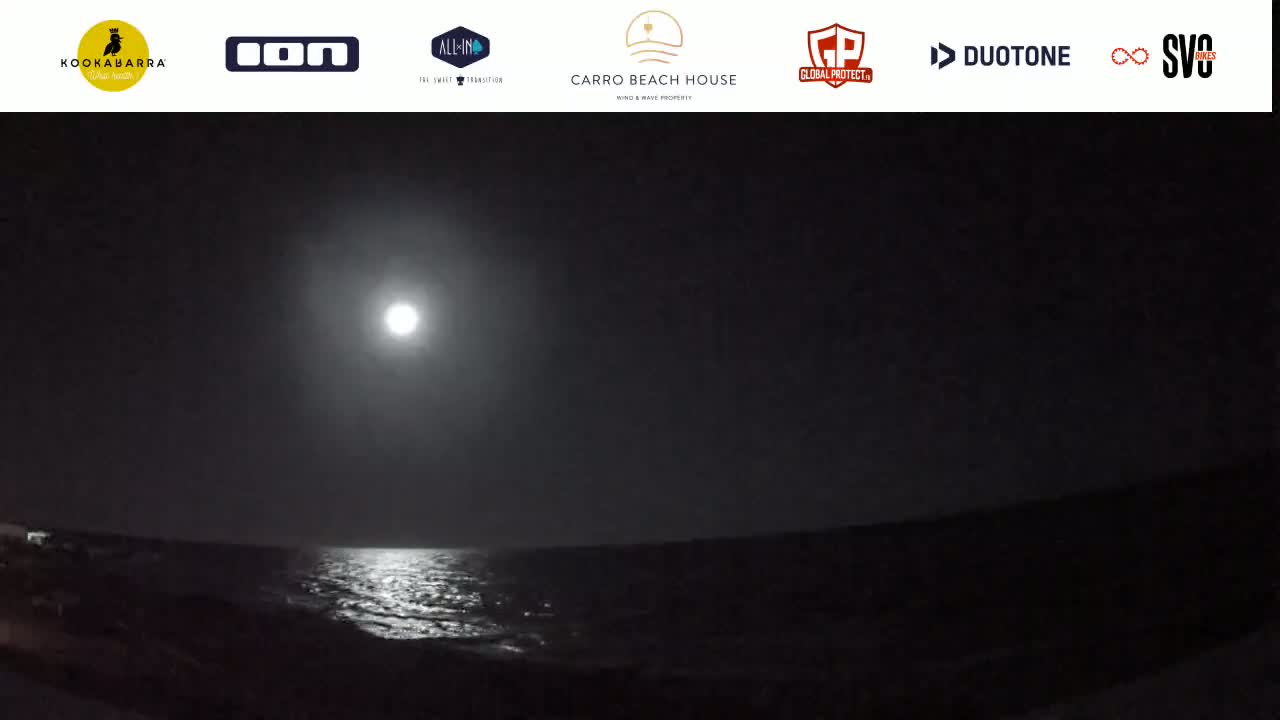 A bright full moon illuminates a dark ocean at night.