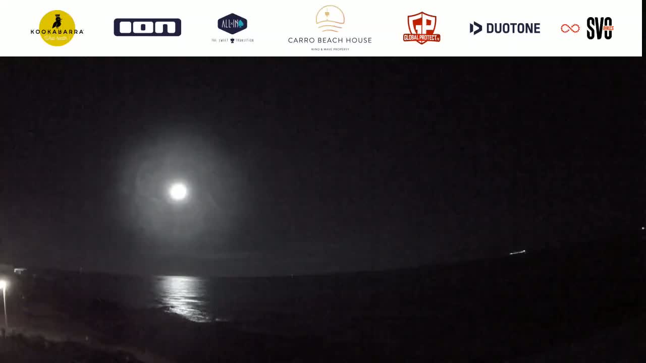 A bright moon illuminates a dark night scene over a calm ocean.