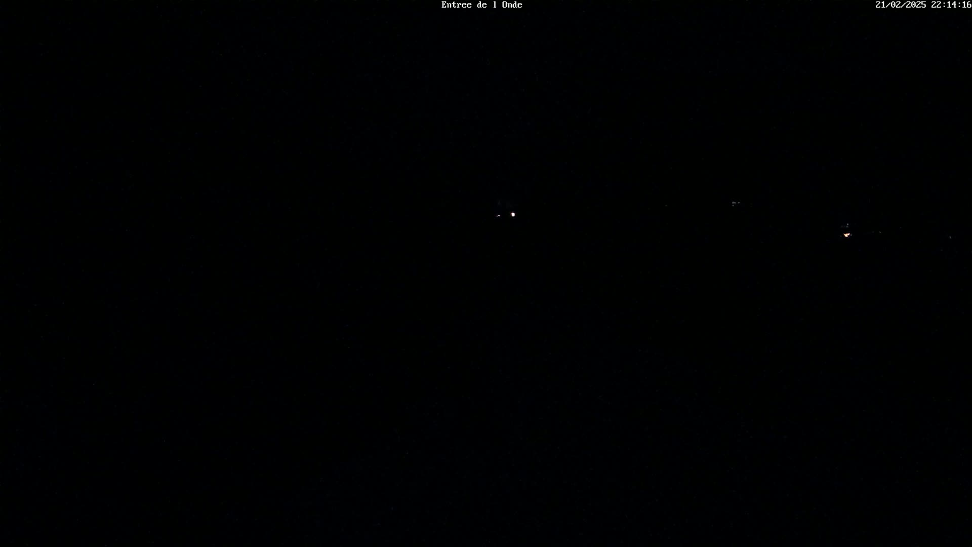 A dark, nighttime scene shows a few faint lights in the distance.