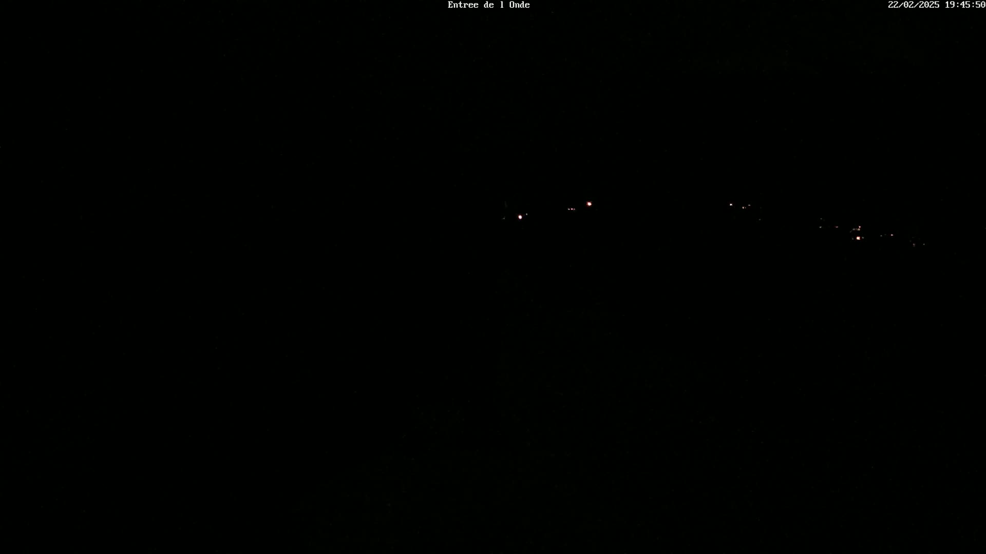 A nighttime, dark view shows a faint line of distant lights.