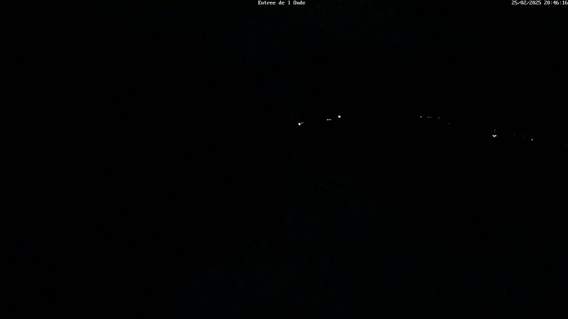 A nighttime, dark image shows a few faint lights in the distance.