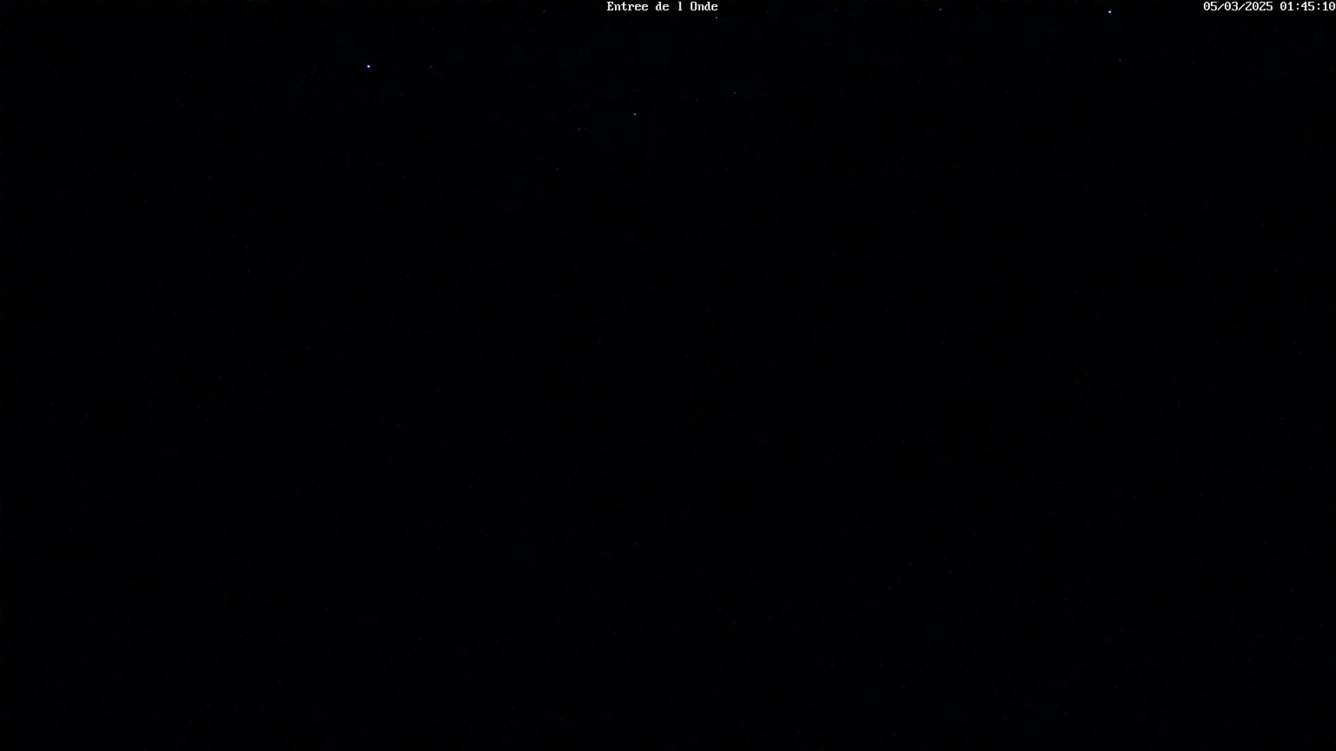 A dark, nighttime scene shows a mostly clear sky with a few faint stars visible.